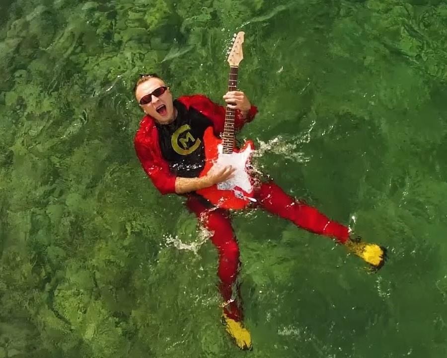 Czadoman (Paweł Dudek) podczas energetycznego występu na żywo, śpiewający na scenie w otoczeniu świateł.
